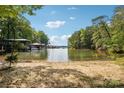 Sandy beach leading to a calm lake with boat docks, framed by lush green trees on a sunny day at 16427 Cozy Cove Rd, Charlotte, NC 28278