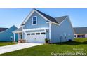 A charming blue two-story home with an attached two-car garage and well-manicured lawn at 122 Tillery Ln # 701P, Mount Gilead, NC 27306