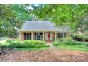 Quaint single-story brick home featuring mature landscaping and a cozy front porch at 2235 Ramblewood Ln, Charlotte, NC 28210