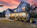 Stunning two-story home with a covered porch, stone accents, professional landscaping and a colorful sunset at 405 Winding Oaks Se Ln, Concord, NC 28025
