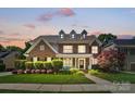 Charming brick two-story home featuring a well-manicured lawn at dusk at 7722 Garnkirk Dr, Huntersville, NC 28078
