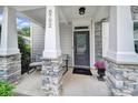 Inviting covered front porch with stone accents and comfortable seating area at 8702 Aspinwall Dr, Charlotte, NC 28216