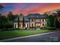 Imposing brick home with black shutters, manicured lawn, mature trees and twilight sky at 1021 Westbury Dr, Matthews, NC 28104