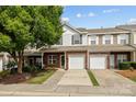 Charming two-story townhome with brick and white siding, featuring a one-car garage and inviting front entrance at 104 Clydesdale Ct, Matthews, NC 28104