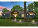 Charming blue home with stone accents, covered porch and landscaped front yard at dusk at 146 Paradise Peninsula Rd, Mooresville, NC 28117
