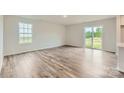 Open-concept living room featuring sliding glass door, large window, and beautiful hardwood flooring at 155 Astor St, Troutman, NC 28166