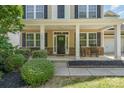 Charming front porch with rocking chairs, stone accents, and lush landscaping creates a welcoming entrance at 15807 Foreleigh Rd, Huntersville, NC 28078