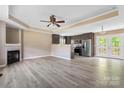 An open living room area featuring a fireplace, ceiling fan and hardwood floors leading into the kitchen at 1806 Red Bird Cir, Concord, NC 28025