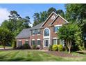 Elegant two-story brick home with a well-manicured lawn, dark shutters, and professionally landscaped garden at 2608 Carmarthen Ct, Matthews, NC 28104