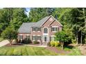Stately two-story brick home with a manicured lawn, lush trees, and professionally landscaped front yard at 2608 Carmarthen Ct, Matthews, NC 28104