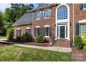 Charming brick home showcasing a large front window, black shutters, and well-maintained landscaping at 2608 Carmarthen Ct, Matthews, NC 28104