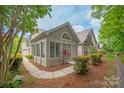 Side view of home showcasing sunroom with large windows, stone accents, and natural landscaping at 2704 Polo Club Blvd, Matthews, NC 28105