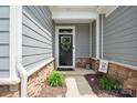 Front entrance features a black door with a wreath, surrounded by stone accents and gray siding at 6242 Ashton Park Dr, Denver, NC 28037