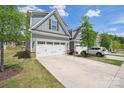 Two-car garage with white doors and a concrete driveway, siding is gray and stone at 6242 Ashton Park Dr, Denver, NC 28037