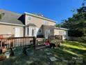 Back exterior showing a large wooden deck with multiple entrances and exits from the house and a well-manicured lawn at 944 Evian Ln, Matthews, NC 28015