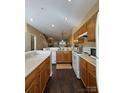 Functional kitchen with wood cabinets, white appliances, and hardwood floors extending into the open floor plan at 1049 Park West Dr, Charlotte, NC 28209
