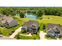 Aerial view of a beautiful brick home with a lush green lawn, long driveway, and a serene lake at 10517 Sable Cap Rd, Mint Hill, NC 28227