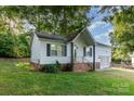 A single-story home with white siding, black shutters, brick foundation and a well-manicured lawn at 1108 Old Dallas Hwy, Dallas, NC 28034