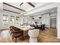 View of dining room with large table, wood beams, and modern light fixture open to the contemporary kitchen space at 1817 Union St, Charlotte, NC 28205