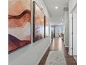 Bright hallway featuring hardwood floors and decorative wall art leading to the dining area at 2585 Blue Sky Meadows Dr, Monroe, NC 28110