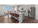 Modern kitchen featuring a large island with seating, granite countertops, and stainless steel appliances at 2585 Blue Sky Meadows Dr, Monroe, NC 28110