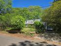 Exterior view of a house surrounded by trees, featuring a driveway and a car parked near the house at 3712 Avalon Ave, Charlotte, NC 28208