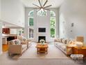 Bright, staged living room with tall ceilings, a ceiling fan, a fireplace and large windows with natural light at 3904 Hounslow Ln, Harrisburg, NC 28075