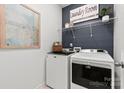 Functional laundry room with modern washer, dryer, shelving, and stylish decor at 566 Mountain View Dr, Monroe, NC 28110
