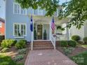 Inviting covered front porch with brick steps, patriotic flags, and manicured landscaping at the facade at 757 Shady Grove Xing, Fort Mill, SC 29708