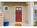 Close-up of a red front door with a decorative round window, offering curb appeal at 8259 Carob Tree Ln, Charlotte, NC 28215