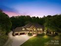 Luxury home at dusk with landscape lighting, large driveway, and stone and stucco exterior at 8451 Ridgewood Rd, Sherrills Ford, NC 28673