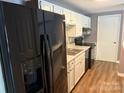 Well-lit kitchen showcasing white cabinets, laminate countertops, black appliances, and wood-look floors at 9325 Old Concord Rd # D, Charlotte, NC 28213