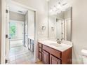 Bright bathroom featuring a large mirror, vanity with dark cabinets, and neutral tile flooring at 1000 E Woodlawn Rd # 408, Charlotte, NC 28209