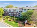 Well-maintained apartment building exterior with manicured landscaping and a prominent community sign at 1000 E Woodlawn Rd # 408, Charlotte, NC 28209