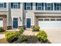 Close-up of a townhouse exterior with a well-manicured garden and a blue front door at 10436 Dalton Woods Nw Ct, Huntersville, NC 28078