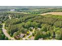 Expansive aerial view of a residential area with lush green trees, several lakes, and a clear blue sky above at 109 Braxton Gate Ct, Mount Holly, NC 28120