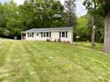 Front of the house with a sloping lawn, classic design, and lush surrounding greenery at 1105 S Church S St, Monroe, NC 28112