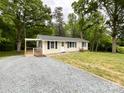 View of the home's front exterior highlighting the gravel driveway and the freshly manicured lawn at 1105 S Church S St, Monroe, NC 28112