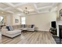 Bright living room boasts tray ceilings, hardwood floors, fireplace, and neutral decor at 16019 Kelby Cv, Charlotte, NC 28278
