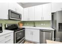 Well-equipped kitchen with stainless steel appliances, white cabinets, green backsplash and modern fixtures at 2125 Southend Dr # 339, Charlotte, NC 28203
