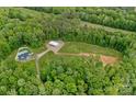 Stunning aerial view of property featuring pool, home, metal building, and wooded acreage at 270 Worthington Dr, Mt Ulla, NC 28125