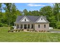 Charming brick home featuring a covered front porch and lush green lawn with mature trees at 270 Worthington Dr, Mt Ulla, NC 28125