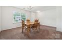 Bright dining room featuring carpet, a wooden table with four chairs, and a window at 3512 Gibbon Terrace Ct, Charlotte, NC 28269