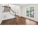 Bright foyer with hardwood floors, staircase, and large window offers a welcoming entrance to the home at 5745 Snapdragon Ln, Huntersville, NC 28078