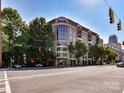 Multi-story condo building with brick facade, large windows, and balconies surrounded by green trees at 718 W Trade St # 704, Charlotte, NC 28202