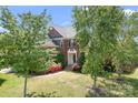 Beautiful home with a manicured lawn, mature trees, brick exterior, and inviting front entrance on a sunny day at 7525 Blackgum Falls Ct, Huntersville, NC 28078