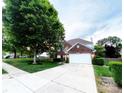 Lovely two-story brick home with manicured lawn, tree, and an attached two-car garage with long driveway at 8218 Lynnewood Glen Dr, Charlotte, NC 28269