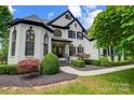 Charming home with well-manicured landscaping, a gray roof, white painted brick and black trim at 8707 Fairview Rd, Charlotte, NC 28226