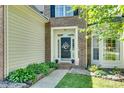 Close-up of the front door featuring detailed molding, a decorative wreath, and professional landscaping at 9700 Stewart Spring Ln, Charlotte, NC 28216