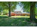 Spacious backyard with a wooden deck, mature trees, and ample green space for outdoor activities at 1004 Midwood Dr, Monroe, NC 28112